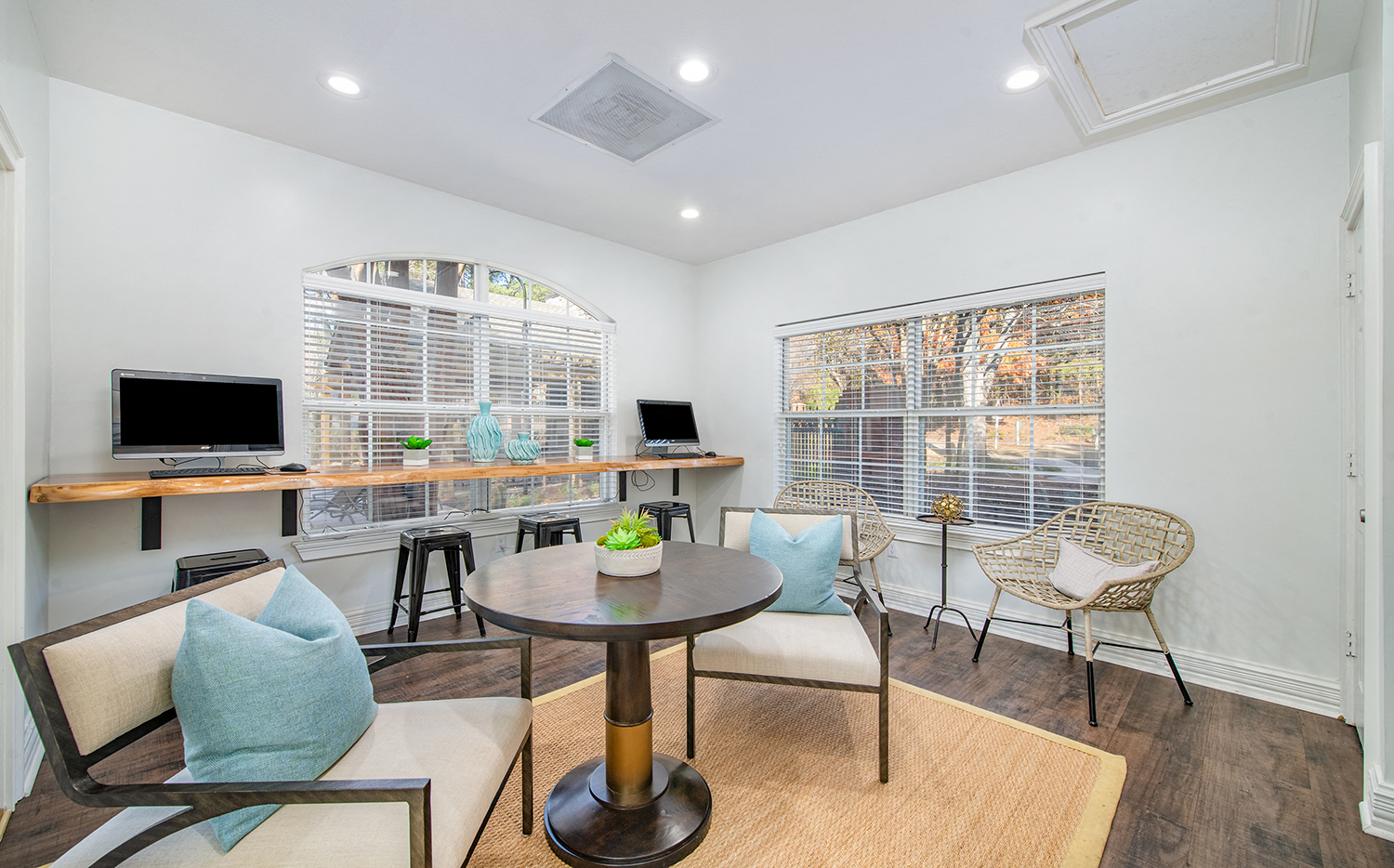 a living room with chairs and a table and two computers