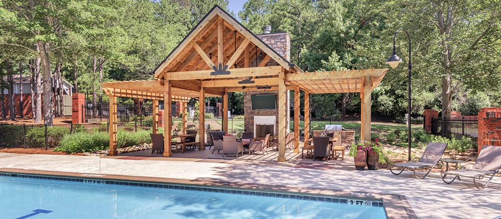 a backyard with a pool and a pavilion with chairs and tables