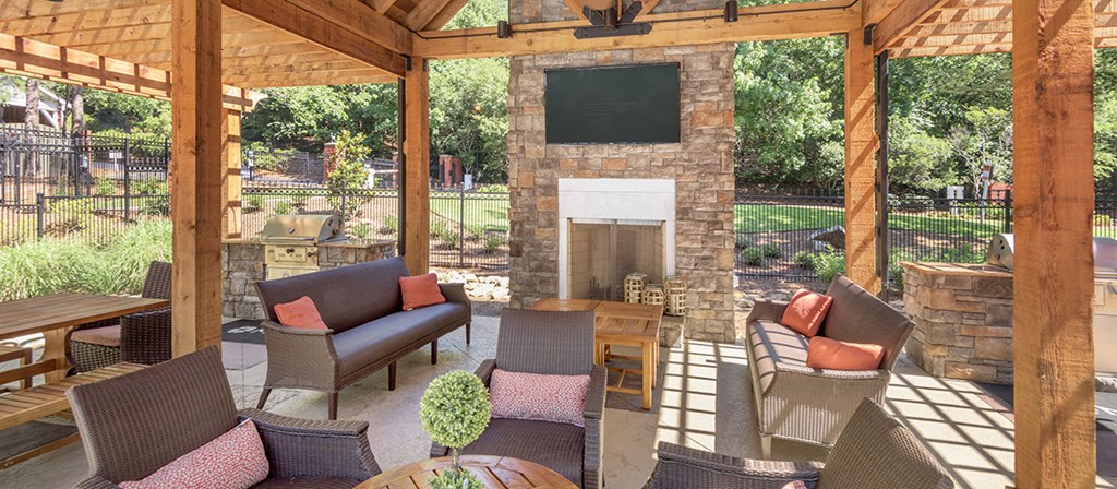 a covered patio with a stone fireplace and furniture