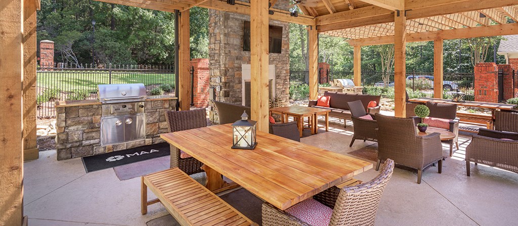 a covered patio with tables and chairs and a grill
