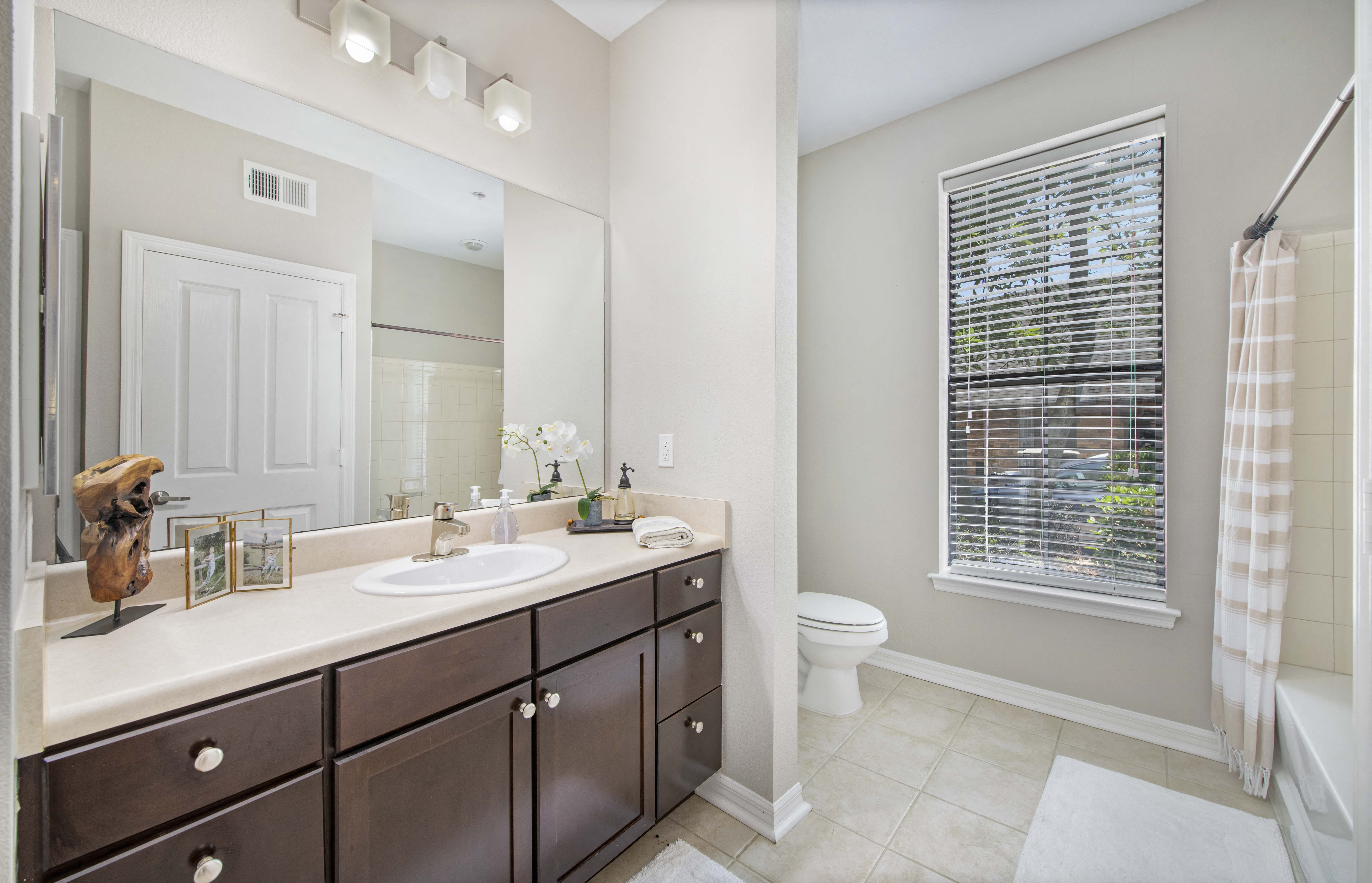 a bathroom with a large mirror and a sink and a toilet