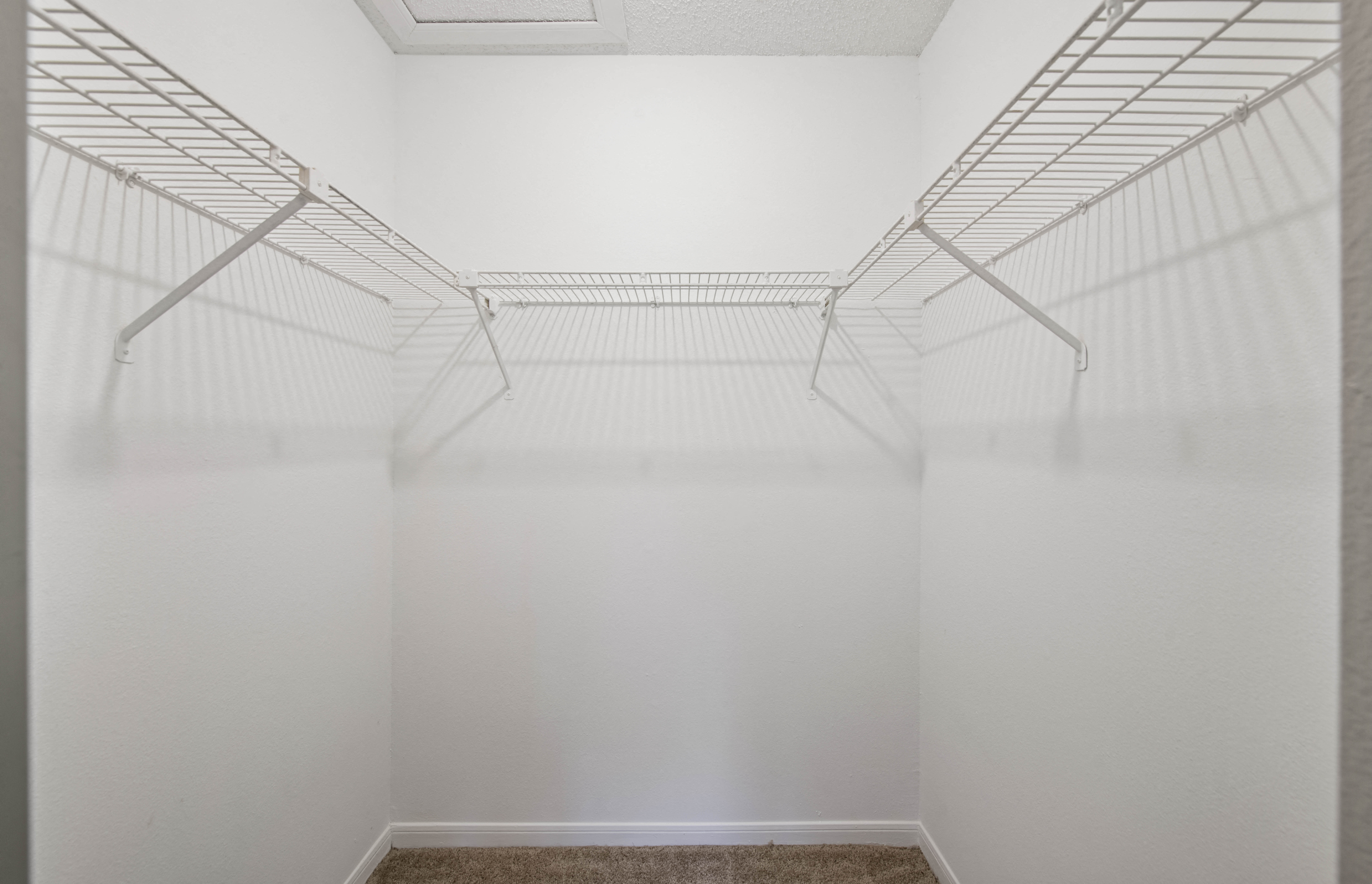 a walk in closet with white walls and wire shelving