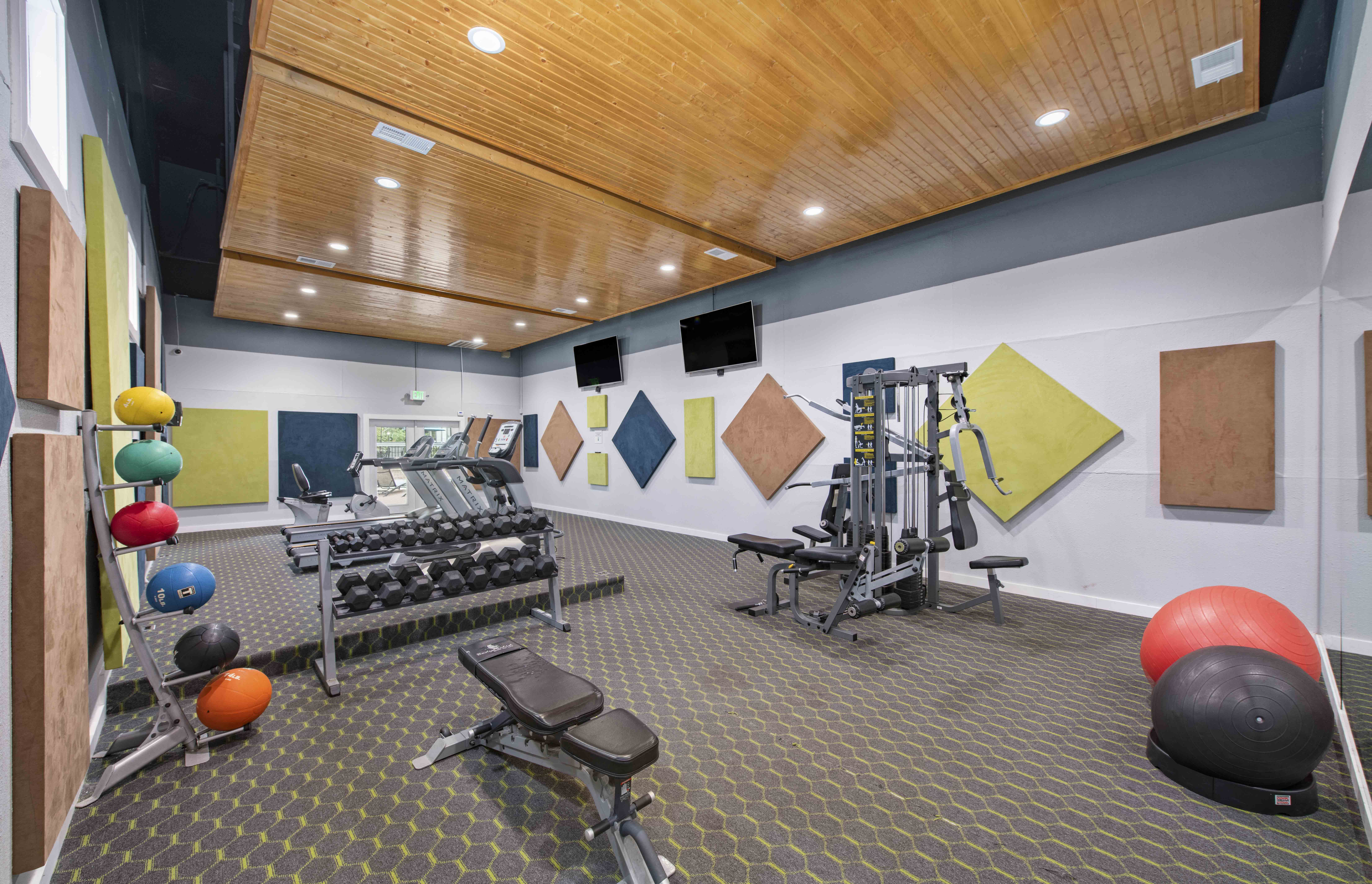 a gym with weights and other exercise equipment in a building with a wooden ceiling