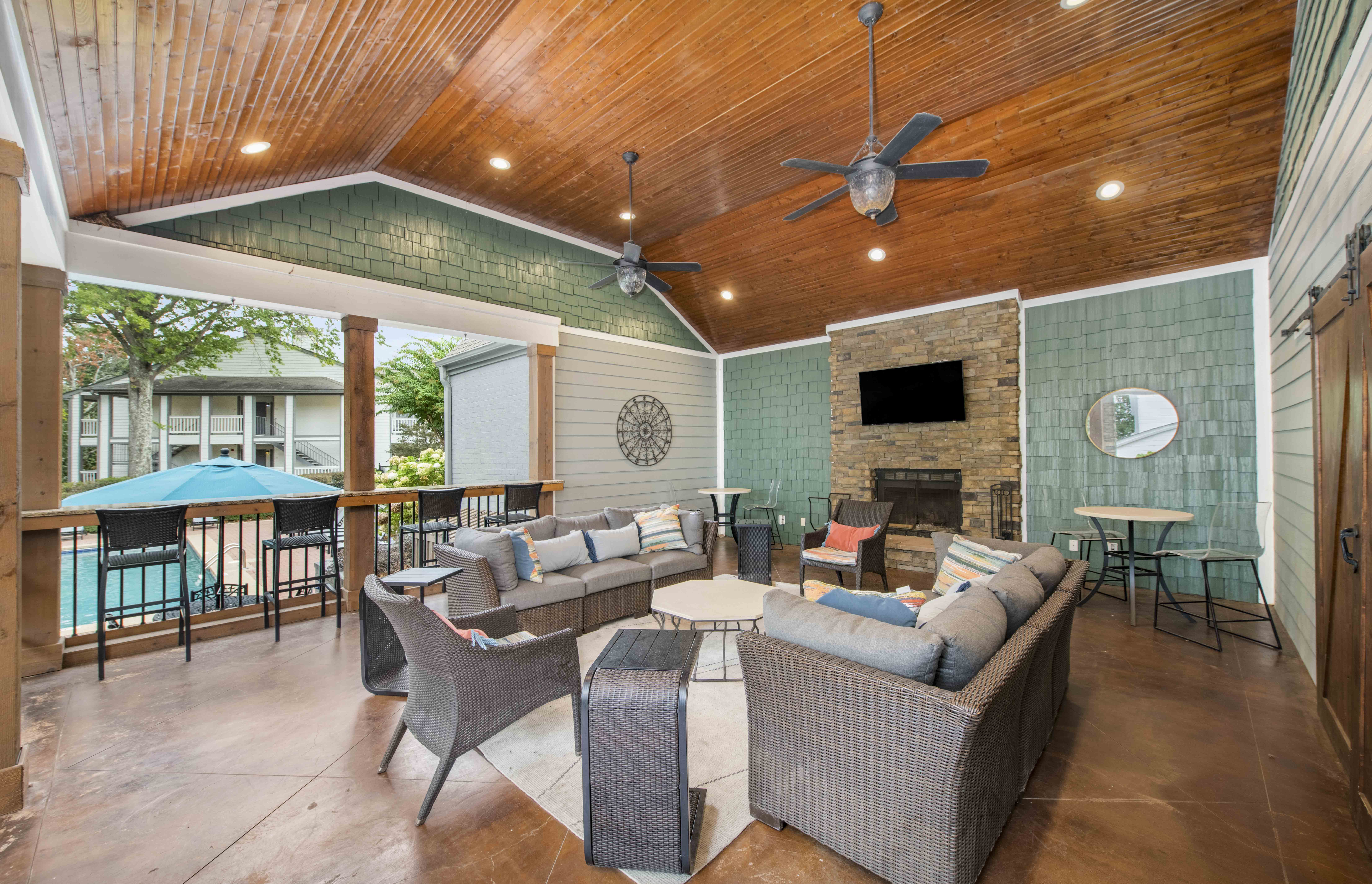 a covered patio with couches and chairs and a fireplace