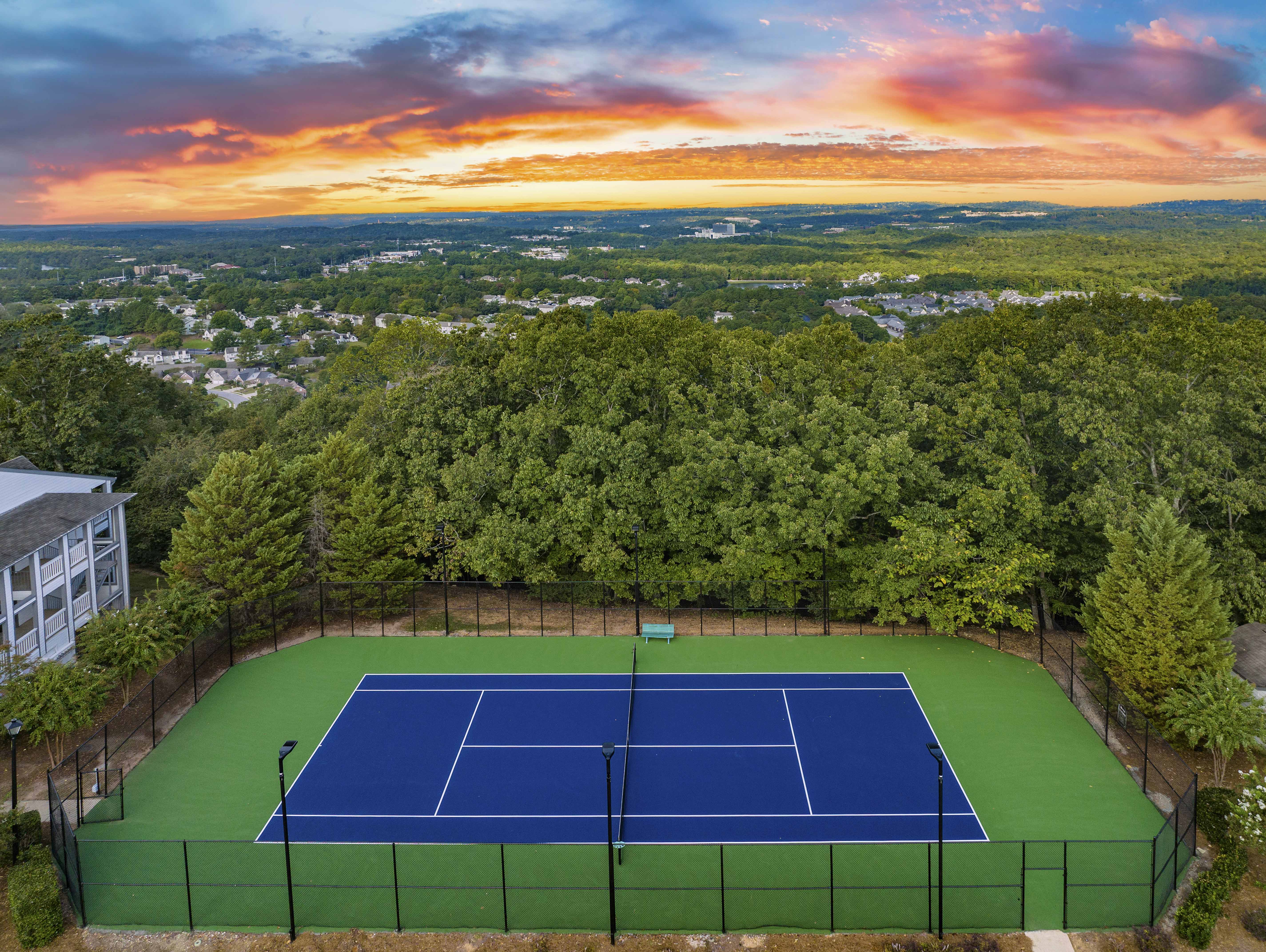 an aerial view of a tennis court with a sunset in the background
