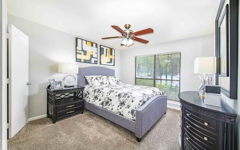 A bedroom with a bed, nightstands, and a ceiling fan.