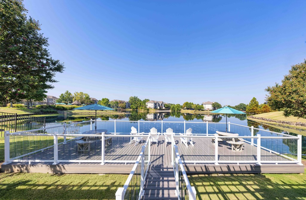 a composite deck overlooking a lake with a dock with chairs and umbrellas