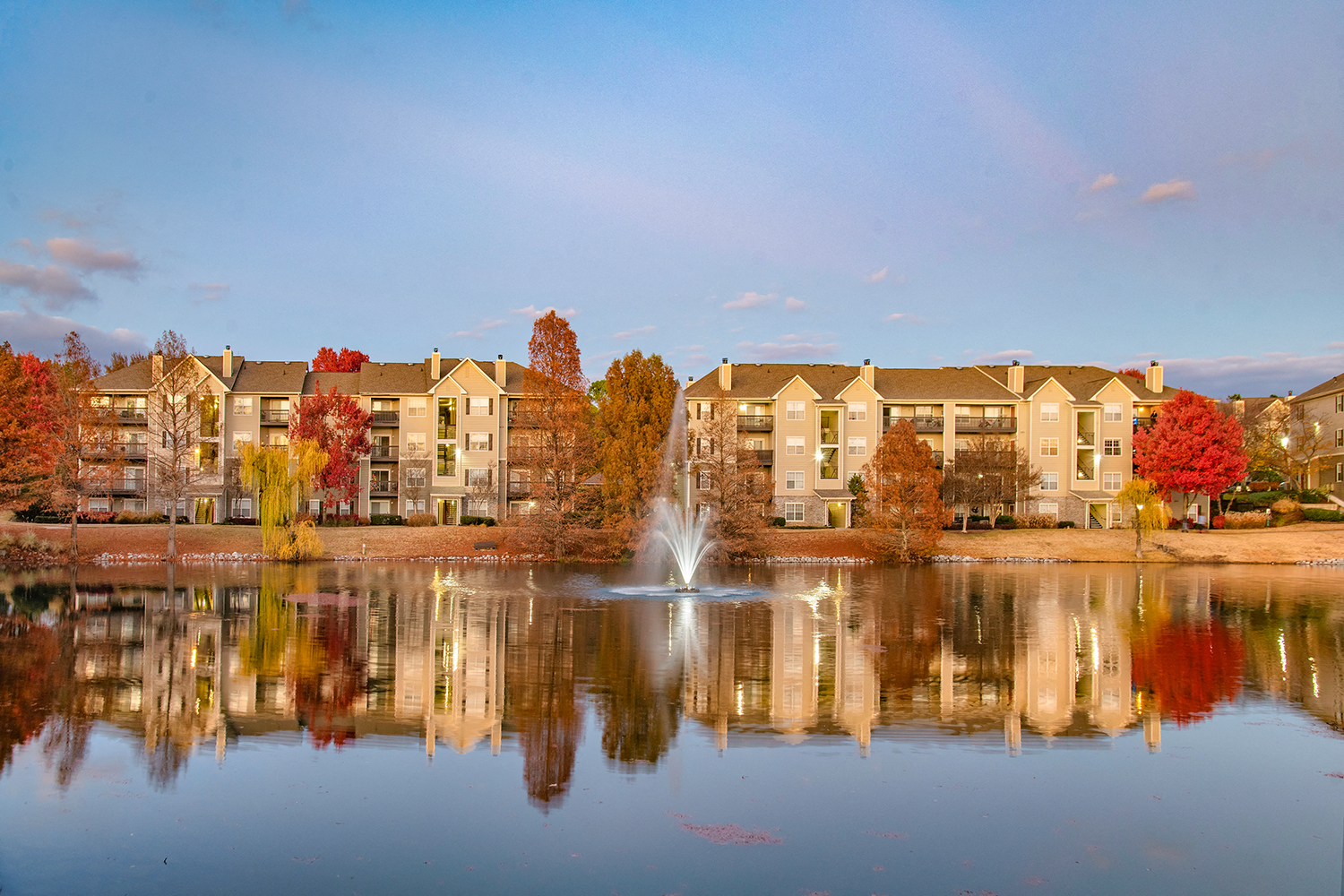 an image of a pond with a fountain in front of an apartment building