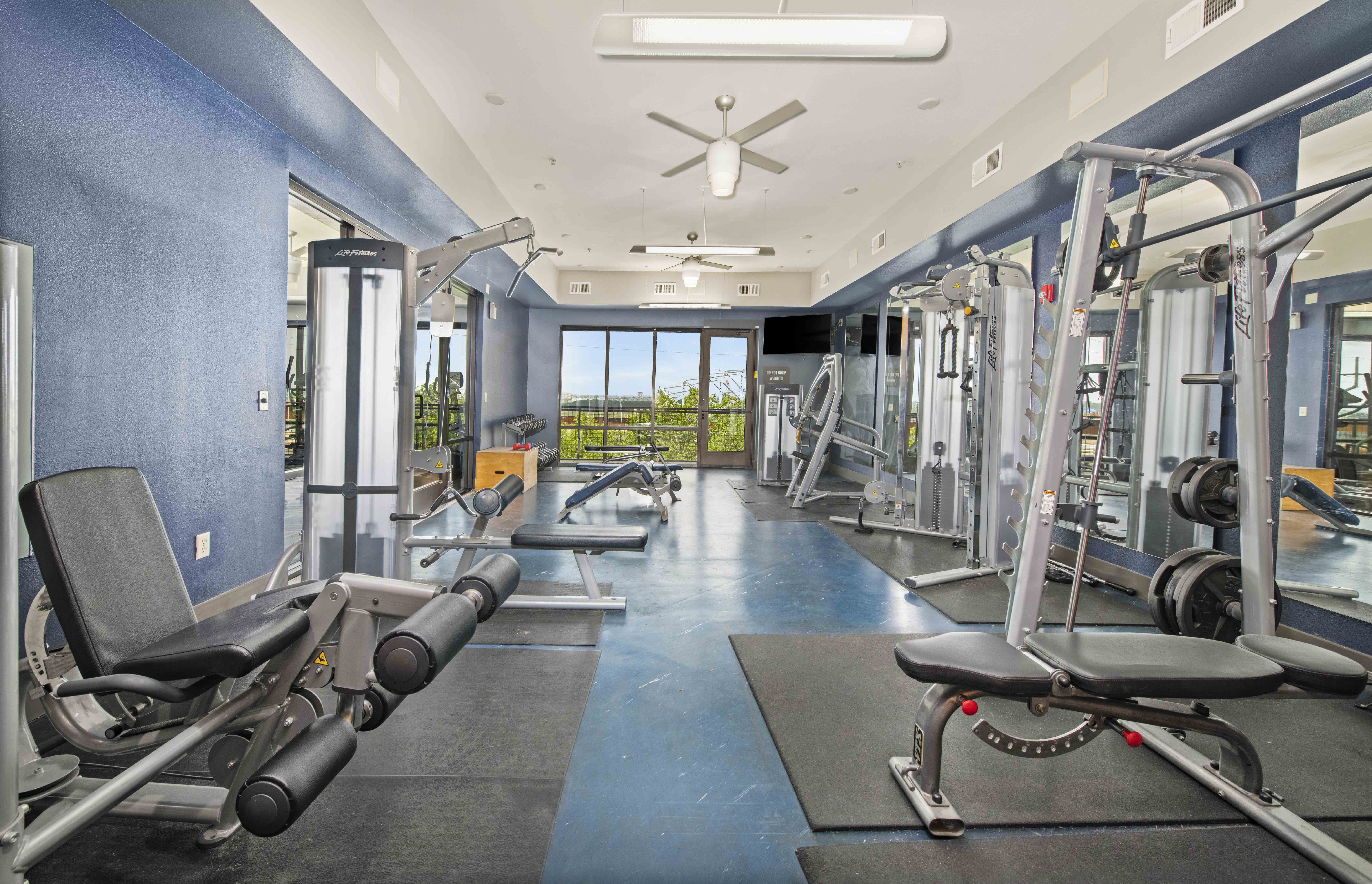 a gym with weights and cardio equipment and a window