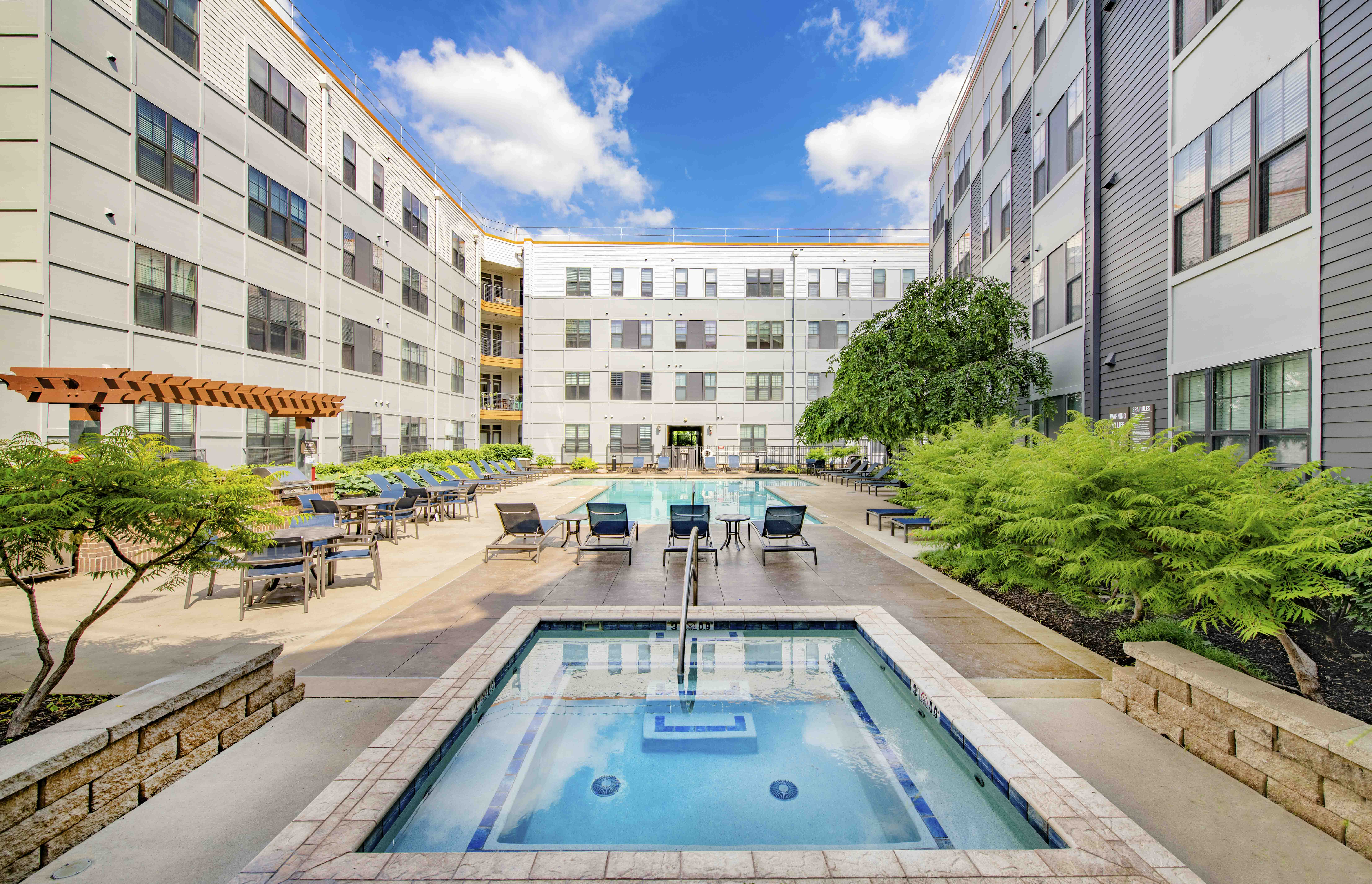 a resort style pool with tables and chairs in front of an apartment building