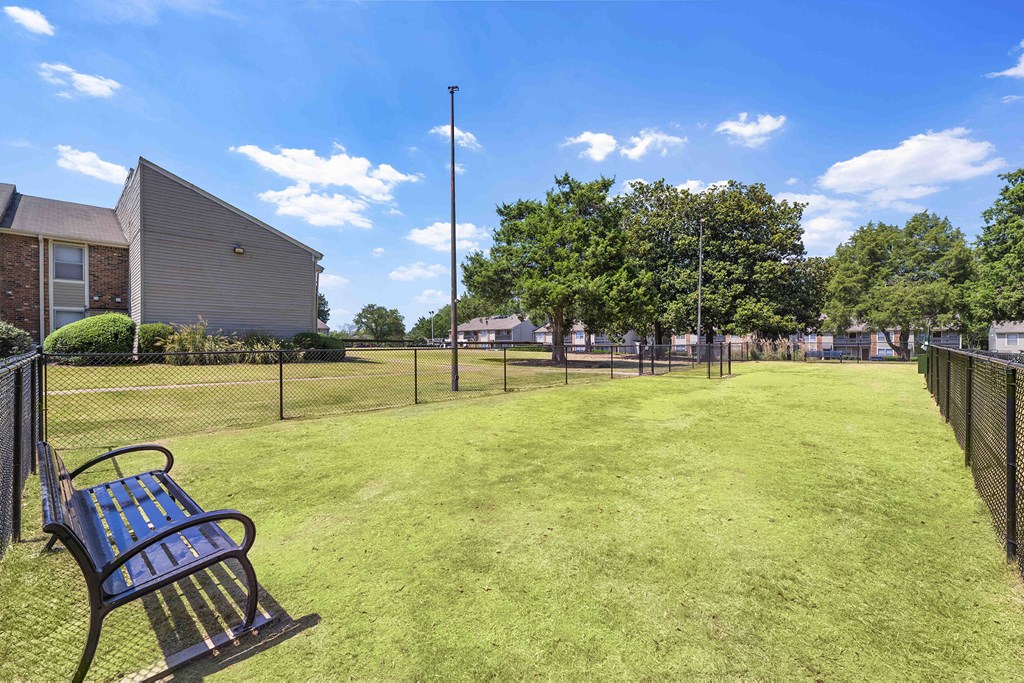 a park bench in a yard with a chain link fence