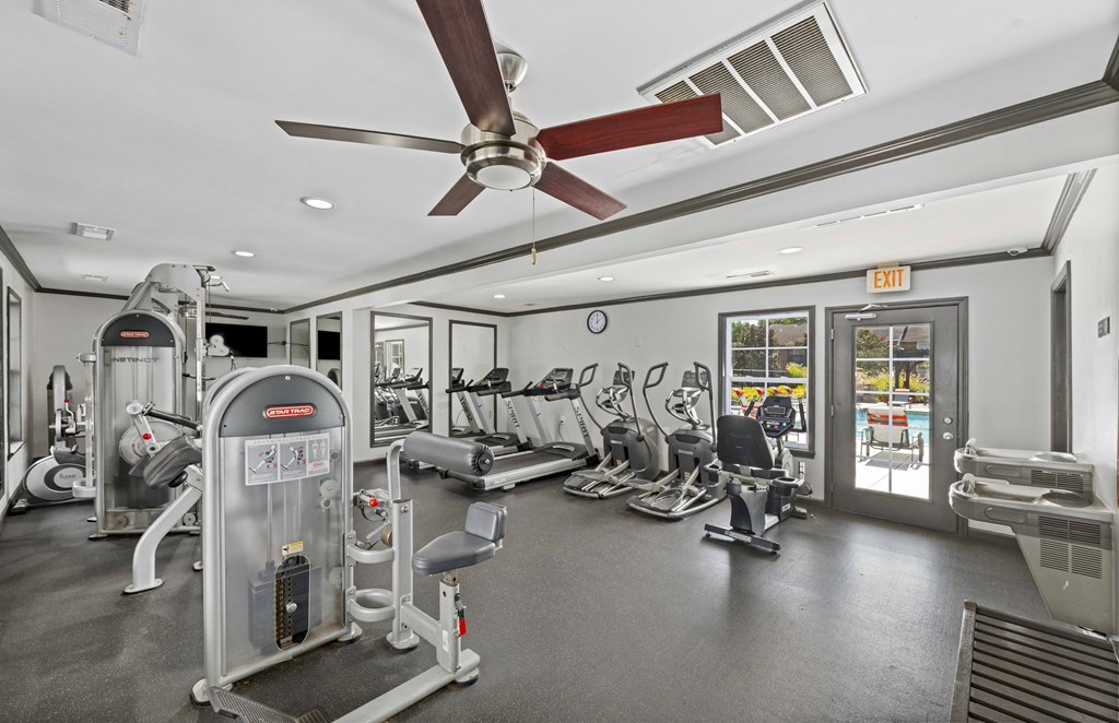 a gym with cardio machines and a ceiling fan