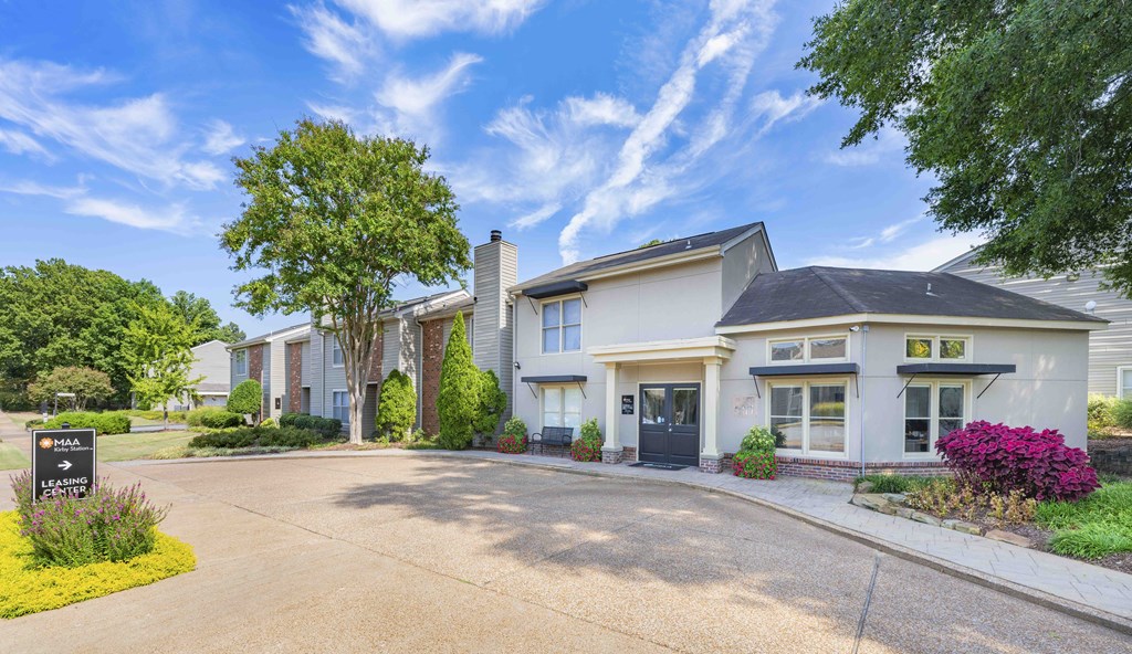 the front of a white house with a driveway and trees