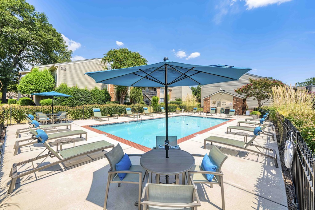 a swimming pool with a table and chairs under an umbrella