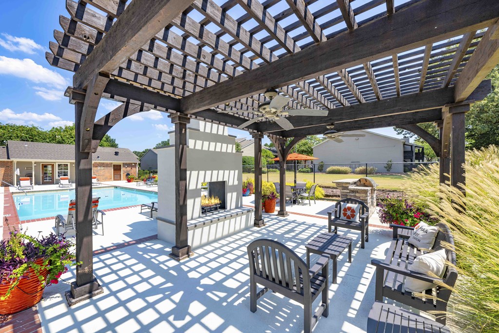 a patio with a pergola next to a swimming pool