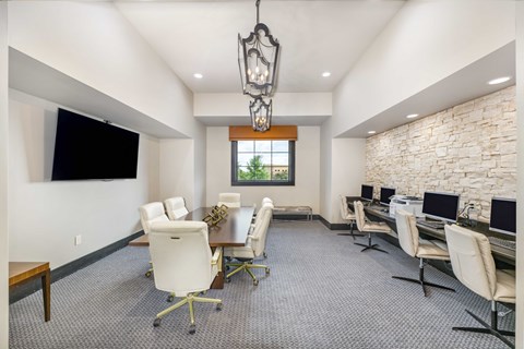 a conference room with desks and chairs and a tv on the wall