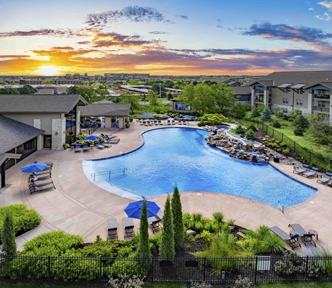 an aerial view of a resort style swimming pool at sunset