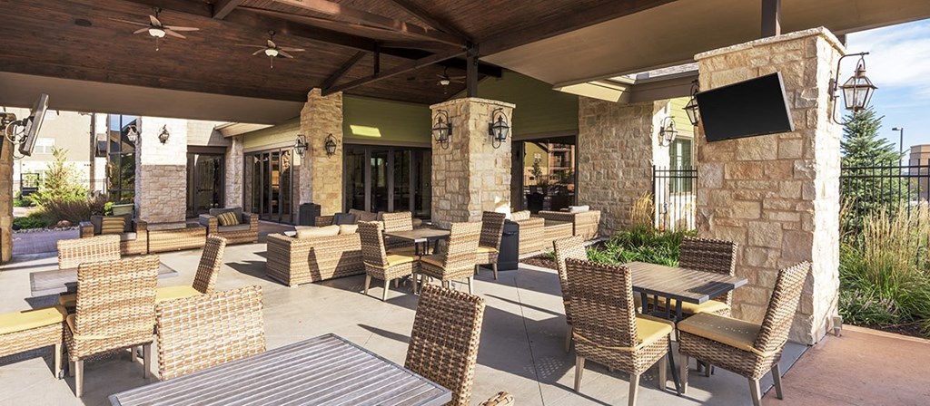 an outdoor patio with tables and chairs and a tv