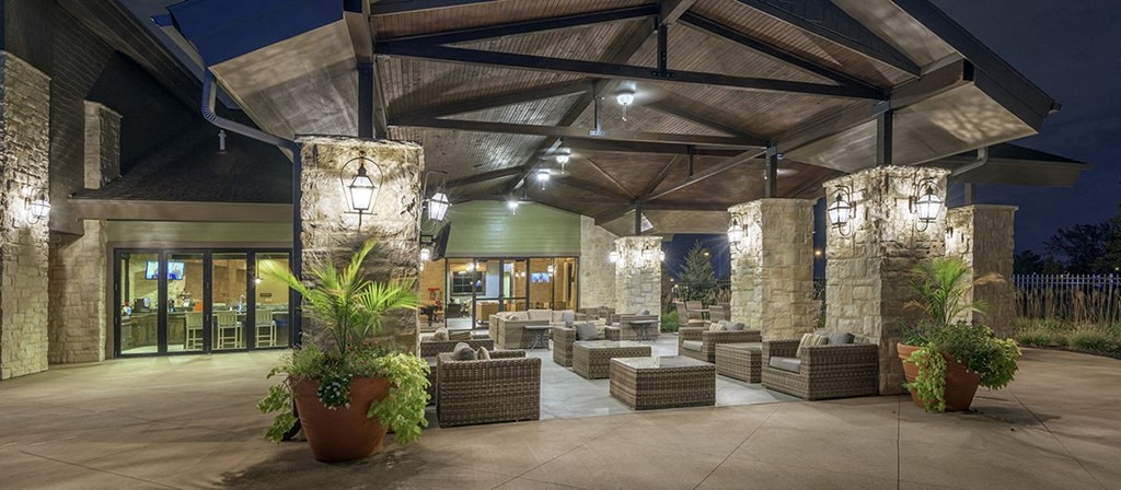 the lobby of a hotel at night with seating and potted plants