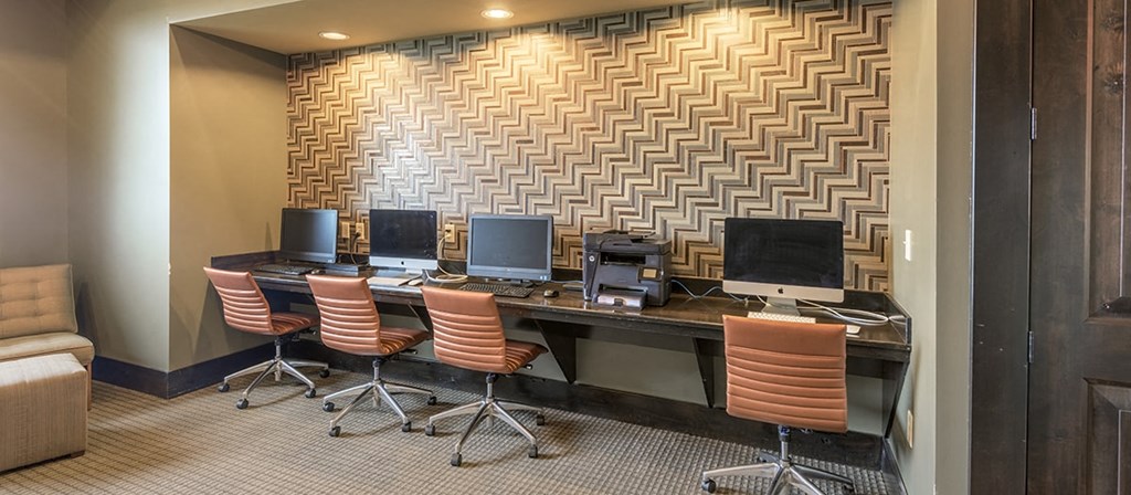 a computer room with four computers on a desk with chairs