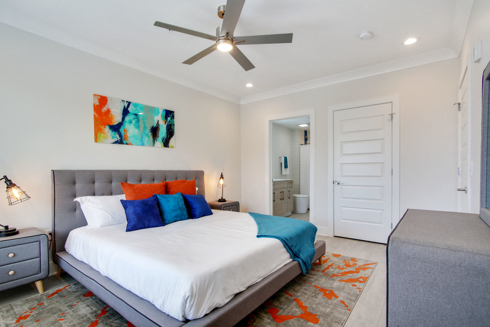 a bedroom with a white bed and a ceiling fan
