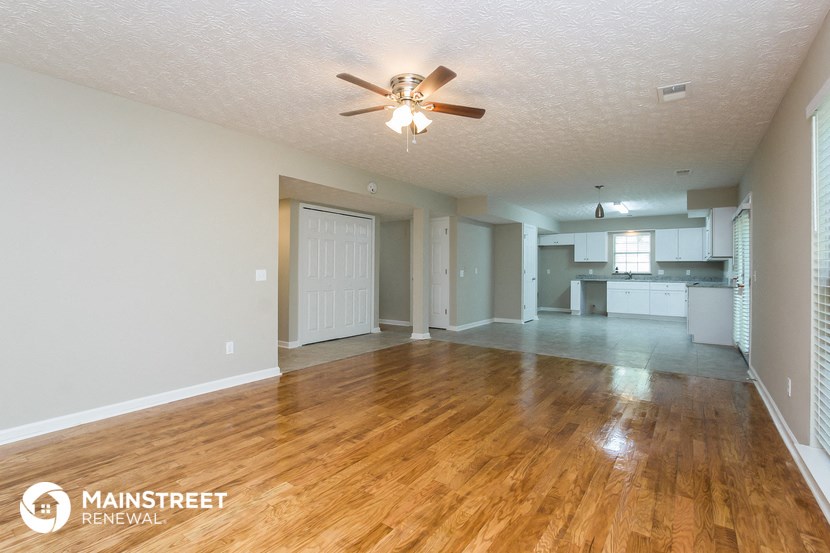 the living room and kitchen of an empty house with a ceiling fan