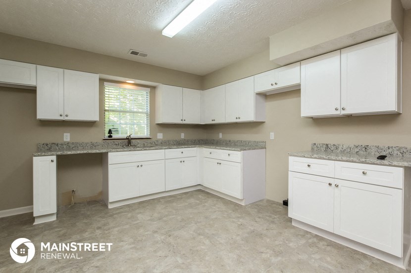 a large kitchen with white cabinets and granite counter tops