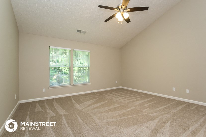 the spacious living room with carpeting and a ceiling fan