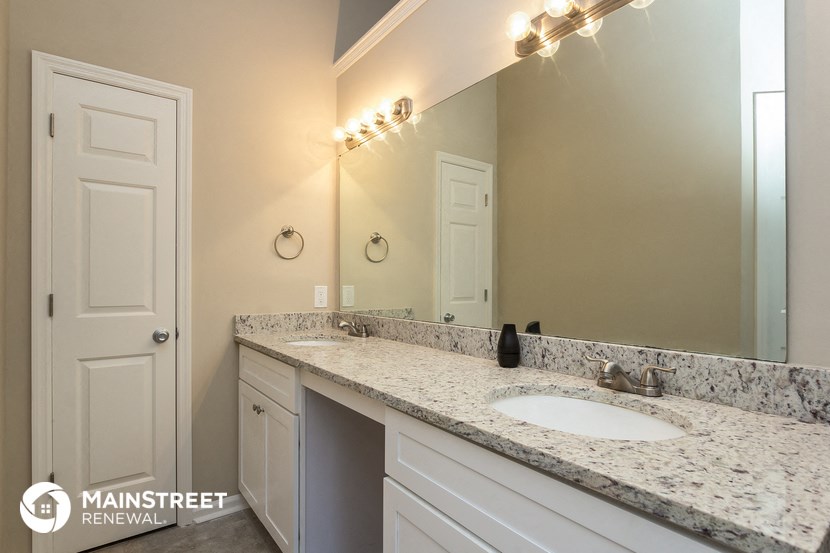 the master bathroom has a large vanity mirror and a sink