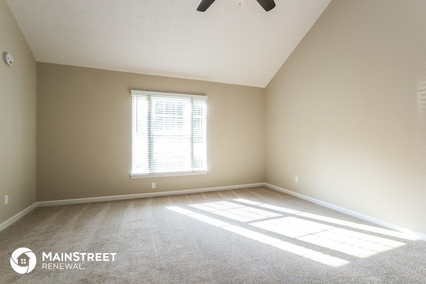 an empty room with a window and a ceiling fan