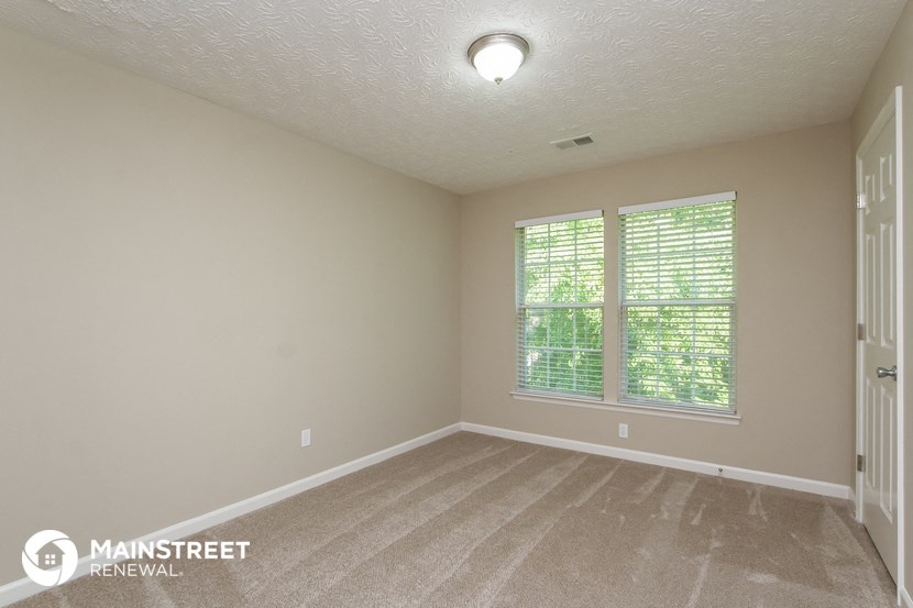 the upstairs bedroom with carpeted flooring and large windows