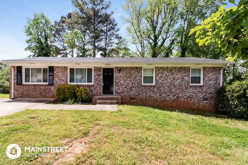 the front of a brick house with a lawn and trees