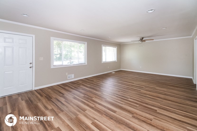 the living room of a home with wooden floors and a white door