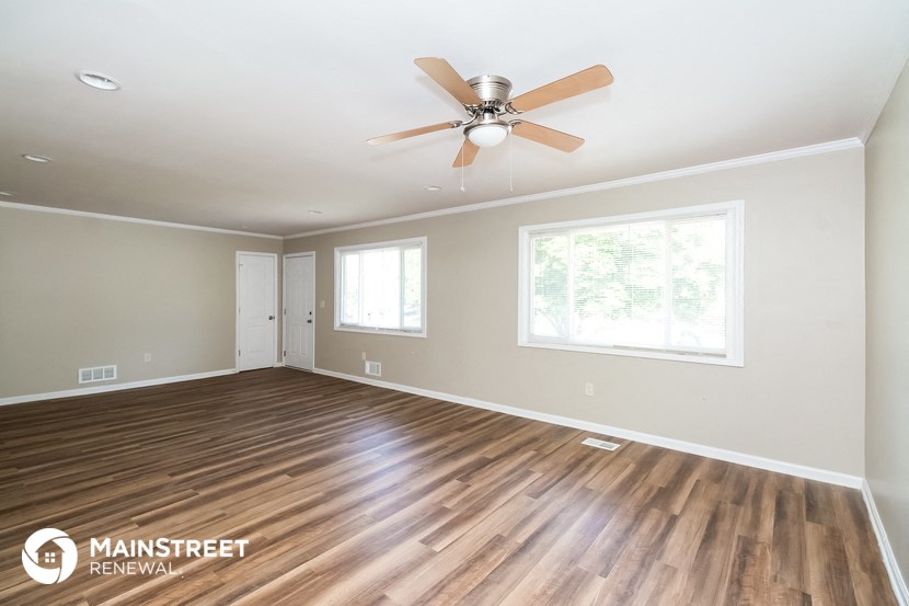 the living room with wood flooring and a ceiling fan