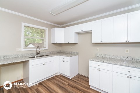 a kitchen with white cabinets and marble counter tops