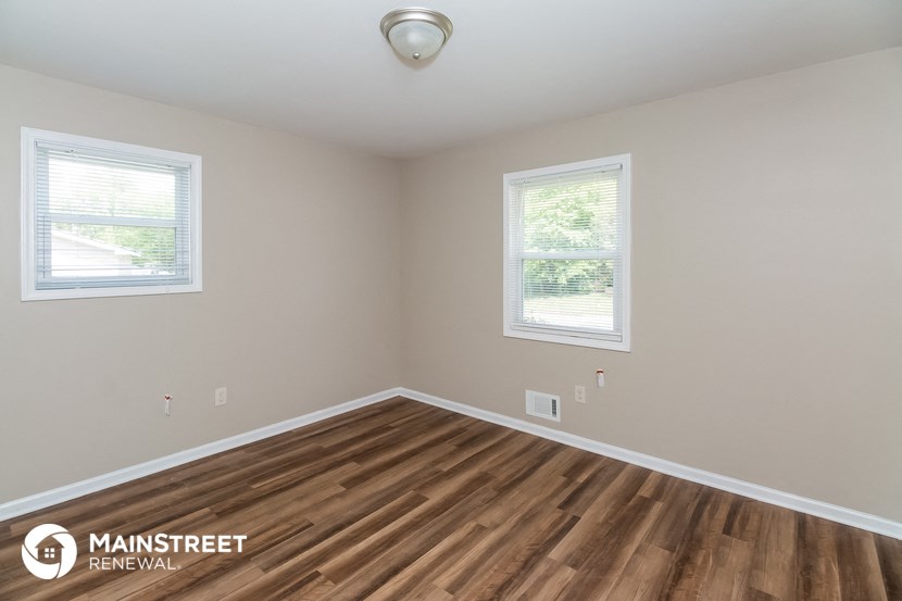 the spacious living room with hardwood flooring and two windows