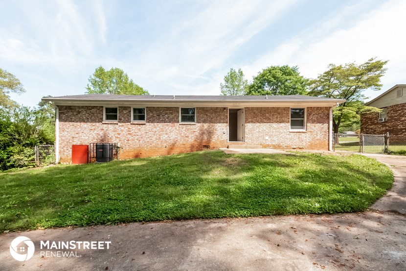 a small brick house with a lawn in front of it