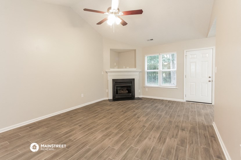the living room of a new home with a fireplace and a ceiling fan