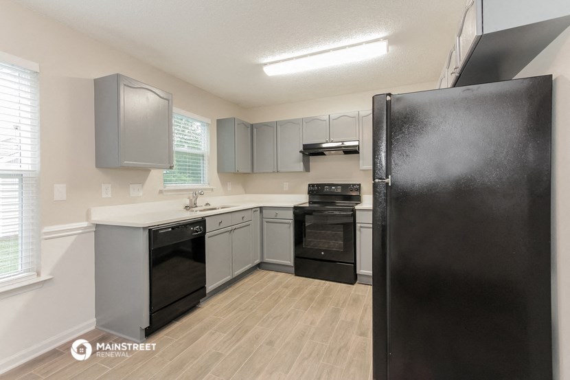 an empty kitchen with black appliances and white cabinets