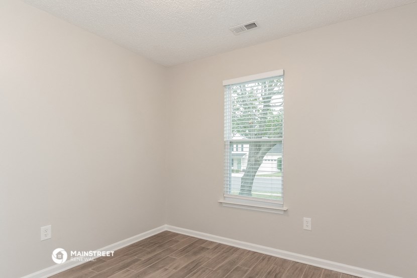 a bedroom with a window and a wooden floor
