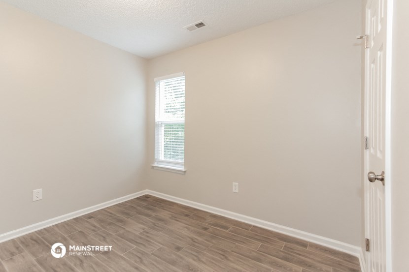 the spacious living room with wood flooring and a window