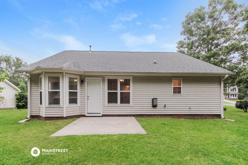 the front of a white house with a lawn and a driveway