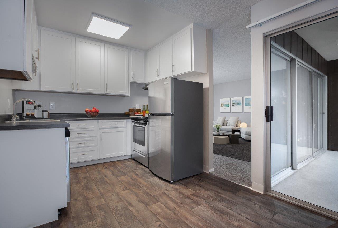 A modern kitchen with white cabinets and a wooden floor.