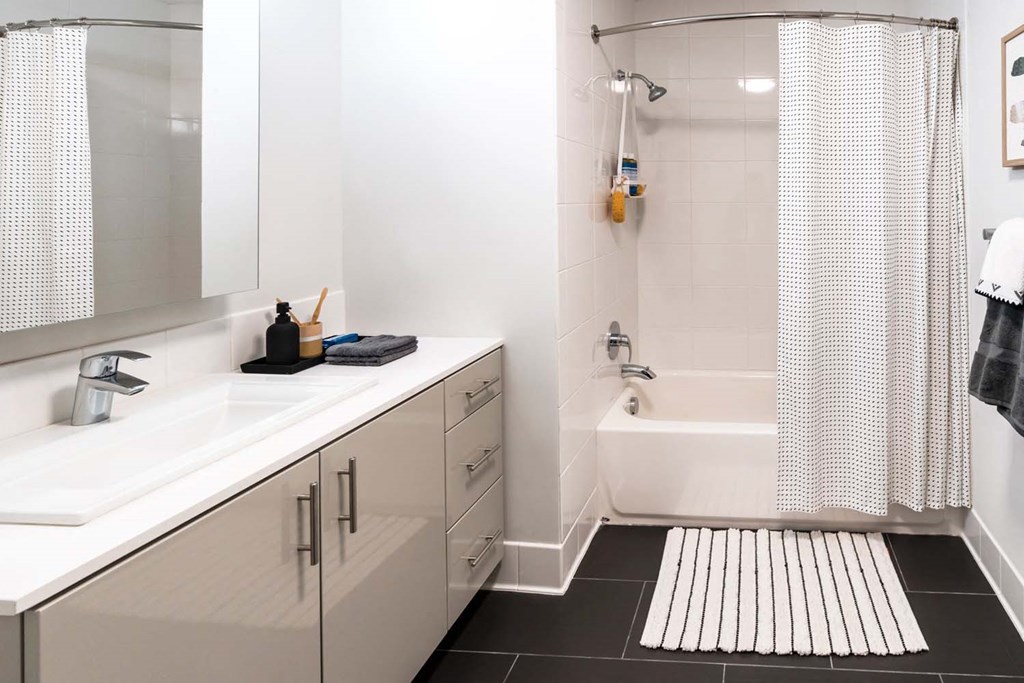 a white bathroom with a tub and a sink and a mirror