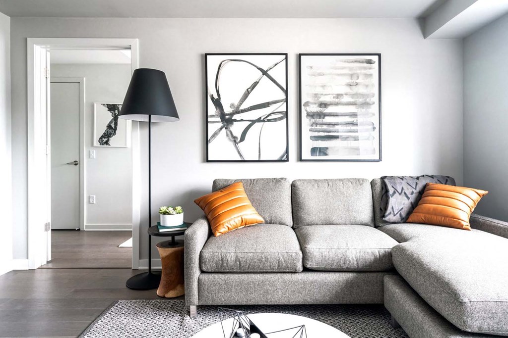 a living room with a grey couch and orange pillows