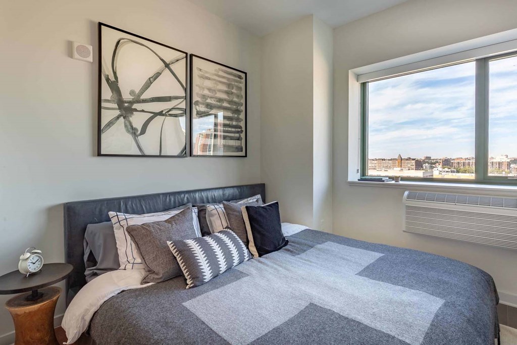 a bedroom with a large window and a bed with pillows