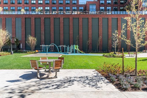 a park with a playground and benches in front of a building