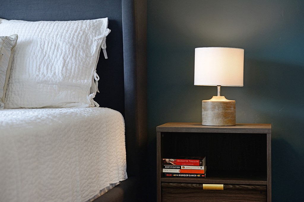 a bedroom with a bed and a table with a lamp on it