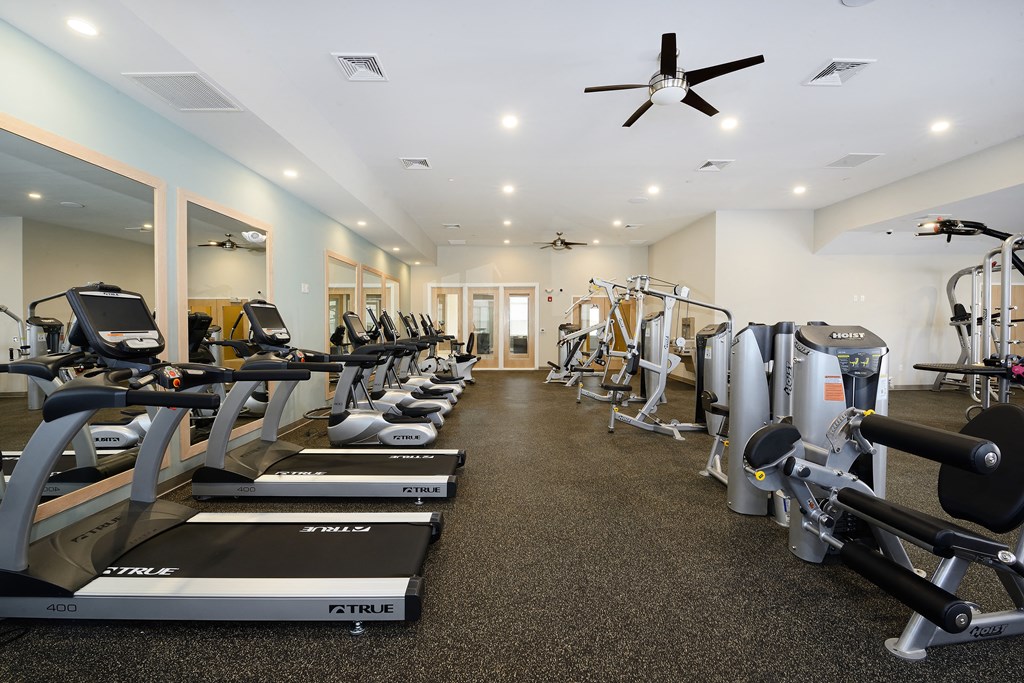 a gym with cardio equipment and weights on the floor