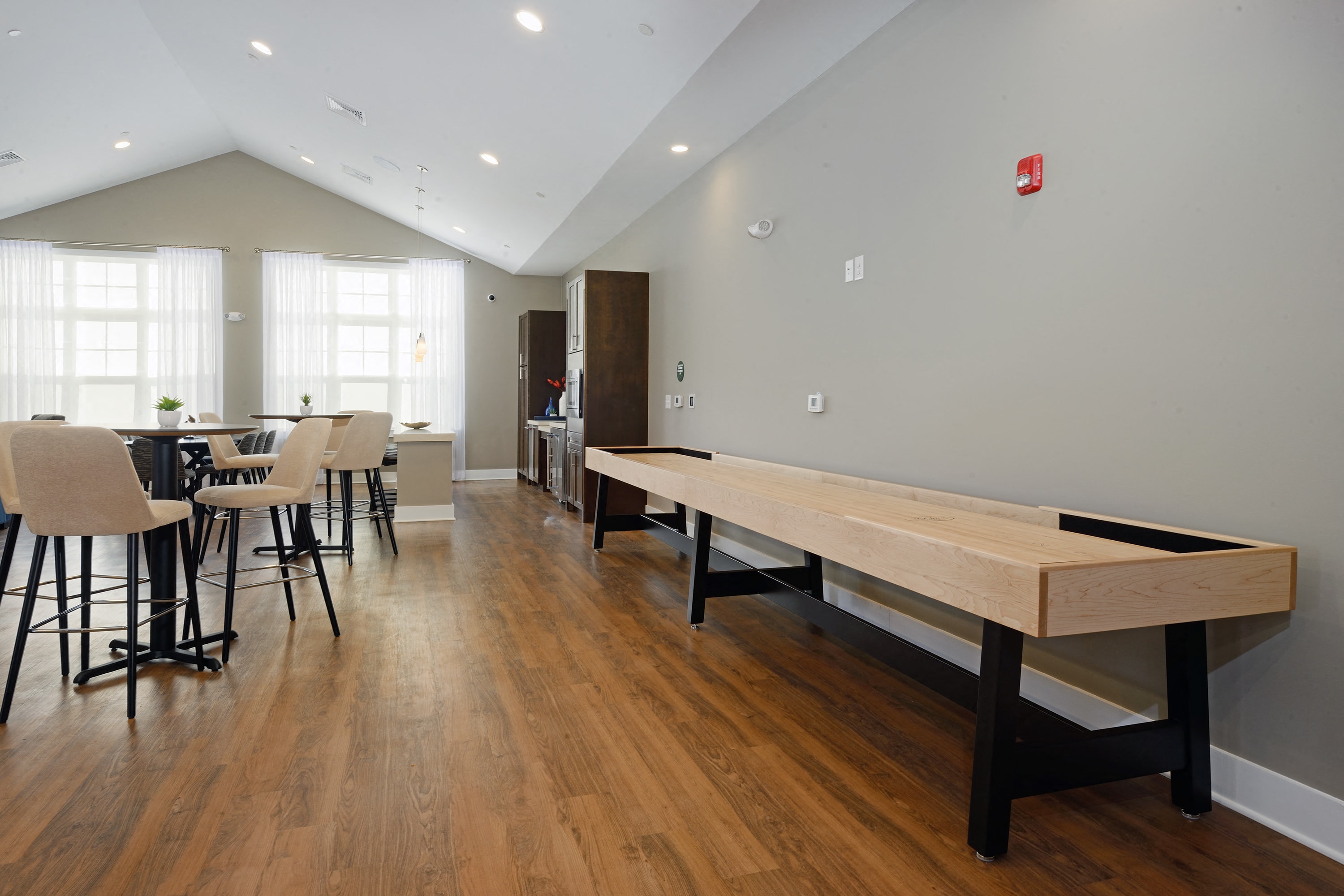 a game room with a shuffleboard table and chairs